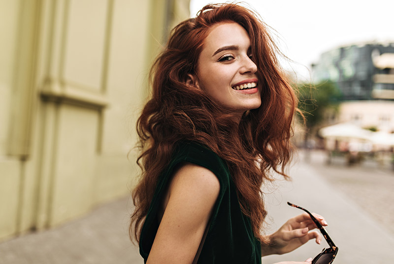 Nice lady smiling holding sunglasses red hair