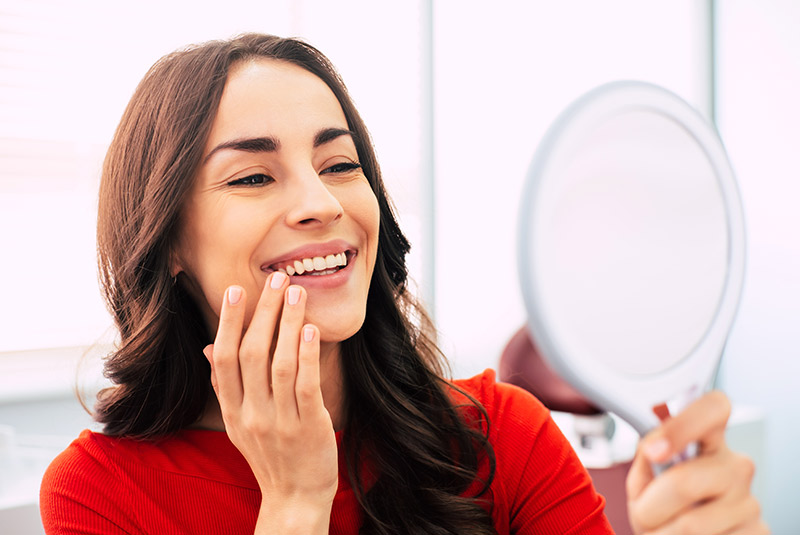 Very nice lady looking into mirror to see her smile makeover