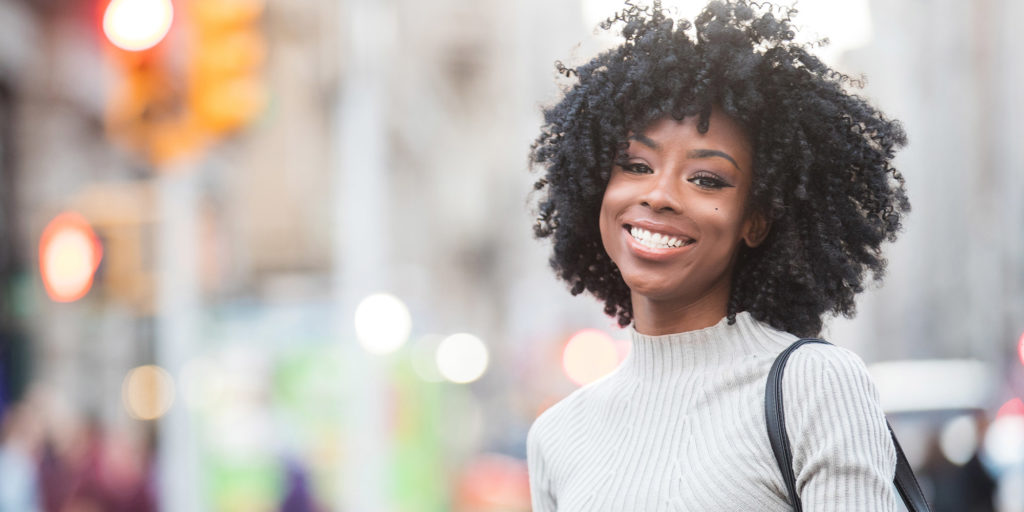 Very nice lady in the streets of New York smiling with dark hair and a light gray sweater